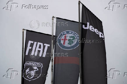 Car logos are seen on banners hung outside a car dealership