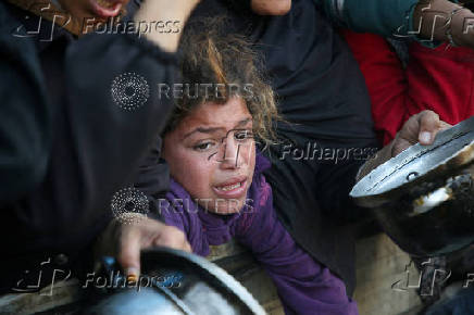 Palestinians gather to receive food cooked by a charity kitchen, in Khan Younis