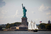 A sailboat passes by the Statue of Liberty in New York Harbor, in New York