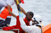 Rescuers disembark a migrant girl from a Spanish coast guard vessel, in the port of Arguineguin