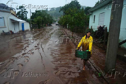 Mulher caminha por rua cheia de lama em Sinimbu (RS)