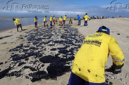 Funcionrios limpam manchas de leo na praia Boca da Barra