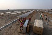 Workers install solar panels at the Khavda Renewable Energy Park of Adani Green Energy Ltd (AGEL), in Khavda