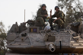 Israeli soldiers rest on top of a tank, near the Israel-Gaza border