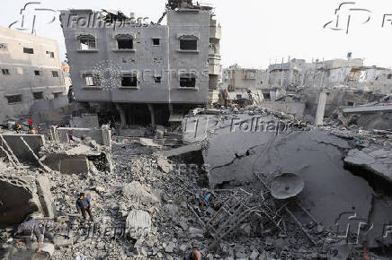 Palestinians inspect damage at the site of an Israeli strike on a house, at Nuseirat refugee camp