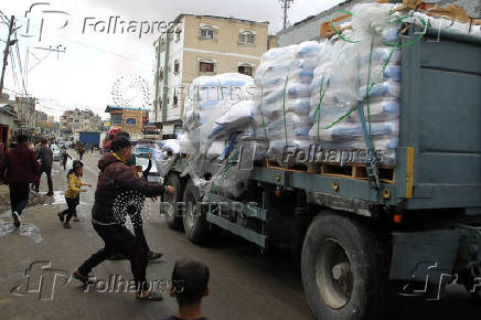 People grab flour bags from a truck after the Israeli military began evacuating Palestinian civilians ahead of a threatened assault on Rafah