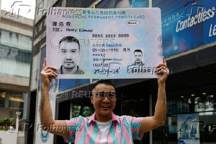 Transgender activist Henry Tse, who won the appeal to change the gender on his ID card, poses outside the immigration office after receiving his new ID card in Hong Kong
