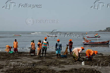 Contract labourers clean a beach on a hot day in Mumbai