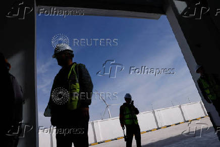 Employees stand near a Taiyuan New Energy Co wind farm, during an organised media tour in Jiuquan