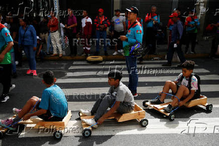 Government supporters participate in a traditional street race with wooden makeshift carts called 