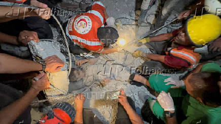 Palestinians work to rescue a child from under the rubble following an Israeli strike, amid the Israel-Hamas conflict, in Nuseirat in the central Gaza Strip