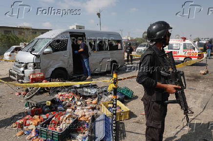 Police officer stands guard near a cordoned damaged vehicle after a suicide blast in Karachi