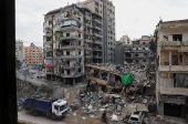 A man rides a motorbike past a damaged building in Beirut's southern suburbs