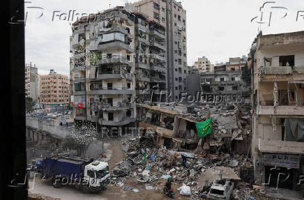 A man rides a motorbike past a damaged building in Beirut's southern suburbs