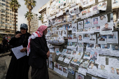 Man looks at pictures of missing people, in Damascus