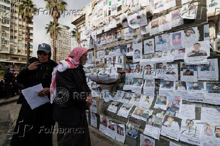 Man looks at pictures of missing people, in Damascus