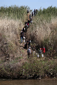 Alawite Syrians, who fled the violence in western Syria, walk near the water of Nahr El Kabir in Akkar