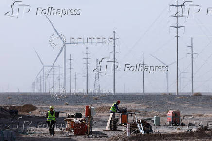 Workers work at a construction site at a Taiyuan New Energy Co wind farm, during an organised media tour, in Jiuquan