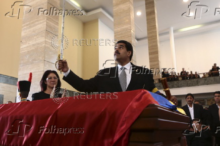 Venezuelan Vice-President Maduro holds a replica of Simon Bolivar's sword over the coffin of Venezuela's late President Chavez in Caracas