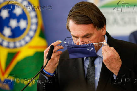 O presidente Jair Bolsonaro tenta colocar  mscara durante evento