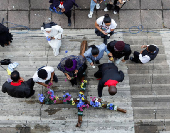 People place flowers on a cross during a silent Good Friday procession in Durban