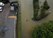 A drone view shows a man canoeing down a flooded street after heavy rain and flooding in Northampton