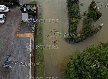 A drone view shows a man canoeing down a flooded street after heavy rain and flooding in Northampton