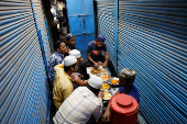 Muslims eat their Iftar (breaking of fast) meal in a small lane outside a closed shop during the fasting month of Ramadan in the old quarters of Delhi