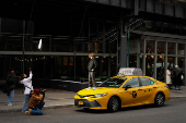 A child stands on a Yellow taxi cab during a photoshoot in New York City