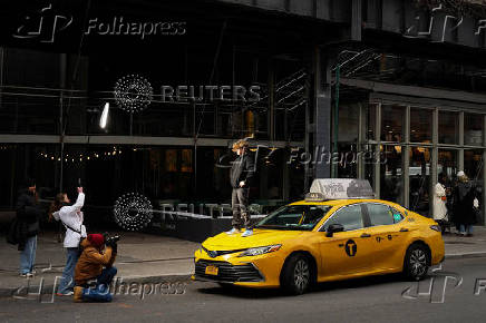 A child stands on a Yellow taxi cab during a photoshoot in New York City