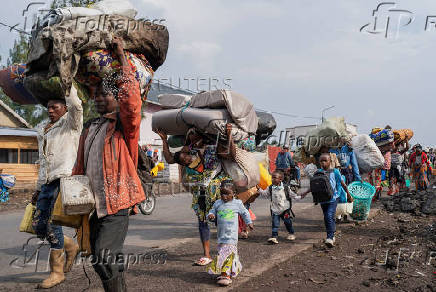 Internally displaced civilians from the camps in Munigi and Kibati, carry their belongings as they flee to Goma