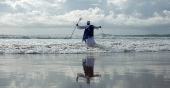 A person takes part in a baptism in the ocean on Good Friday in Durban