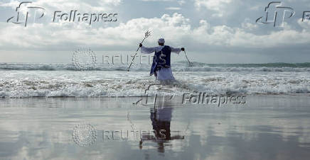 A person takes part in a baptism in the ocean on Good Friday in Durban