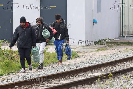 Migrants walk with their belongings in a camp in Grande Synthe