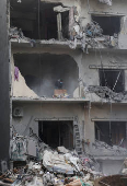 A man clears debris from an apartment in Beirut's southern suburbs