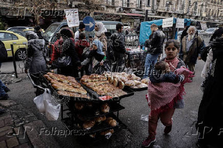 People walk past a street vendor's stall in downtown of Damascus