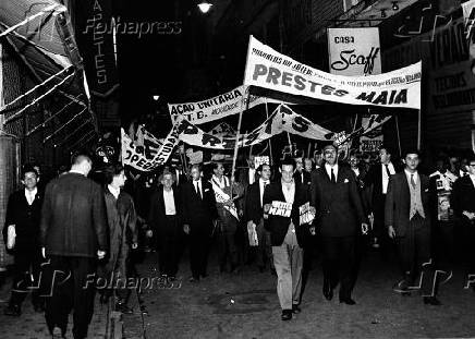 Eleitores marcham exibindo  faixas comemorando a vitoria de Prestes Maia