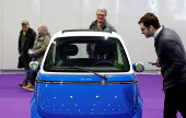 People look at the Microlino EV car, on display at the Everything Electric exhibition