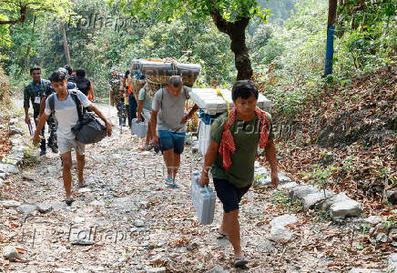 Porters carry VVPAT and EVM during a trek to reach a remote polling station inside Buxa Tiger Reserve forest
