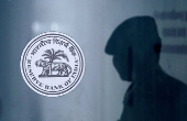 FILE PHOTO: FILE PHOTO: A security guard's reflection is seen next to the logo of the Reserve Bank Of India (RBI) at the RBI headquarters in Mumbai