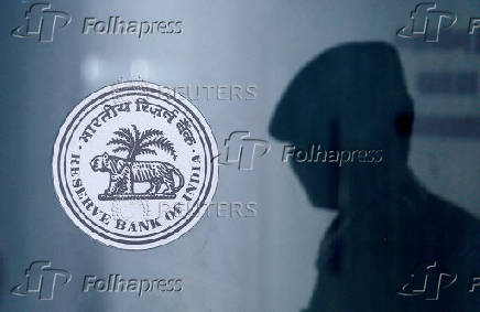 FILE PHOTO: FILE PHOTO: A security guard's reflection is seen next to the logo of the Reserve Bank Of India (RBI) at the RBI headquarters in Mumbai