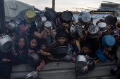 Displaced Palestinians collect donated food in Khan Yunis, southern Gaza