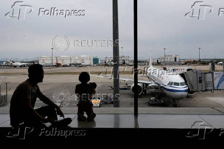 Passengers look at the tarmac as they wait for their flights at the Beijing Capital International Airport, in Beijing