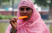 A woman eats an ice cream on a hot summer day in New Delhi
