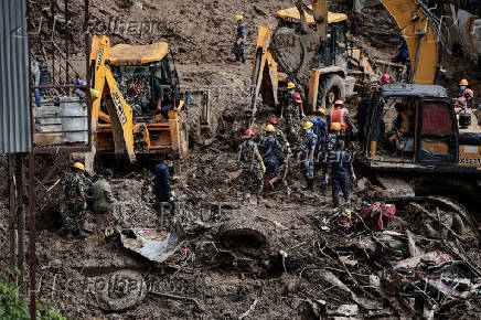 Rescue personnel work to retrieve the bodies of victims from a landslide triggered by heavy rainfall at the Tribhuwan Highway in Dhading