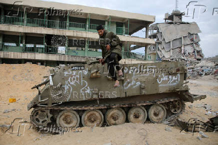 Palestinians look at damaged Israeli military vehicles left behind by Israeli forces in Rafah