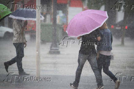 Pedestres se protegem da chuva em Campinas (SP)