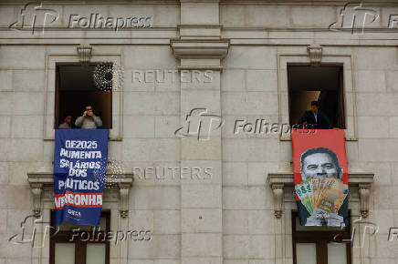 Far-right political party Chega expose banners on the facade of the Portuguese parliament against the wage reinstatement for politicians after the cuts imposed by the Troika, during the debate and vote of the 2025 budget bill on final reading, in Lisbon