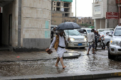 Man walks on a flooded street during rains in Sanaa