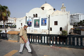 A person walks past electoral campaign posters of presidential candidates in Algiers